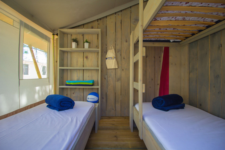 Interieur van safaritent met stapelbedden, kast en raam op Camping Polari in Kroatië.