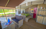 Interior de tienda safari con asientos, comedor, cocina y aire acondicionado en Camping Polari, Croacia.