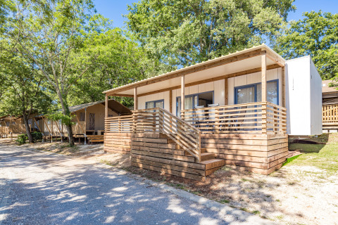 Das Mobile Home Pula mit Holzterrasse im Grünen, umgeben von Bäumen und Natur in sonniger Lage.