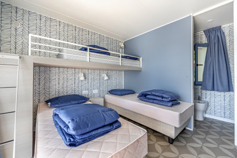 Habitación en Mobile Home Pula de Camping Bijela Uvala, Croacia, con tres camas y decoración moderna.