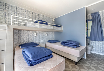 Slaapkamer in Mobile Home Pula op Camping Bijela Uvala, Kroatië, met drie bedden en modern interieur.