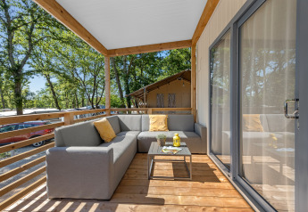 Terraza moderna con sofá gris y cojines amarillos en Mobile home Pula, Camping Bijela Uvala, Croacia.