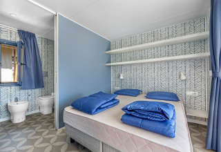 Slaapkamer van Mobile home Pula op Camping Bijela Uvala in Kroatië met blauw beddengoed en moderne stijl.