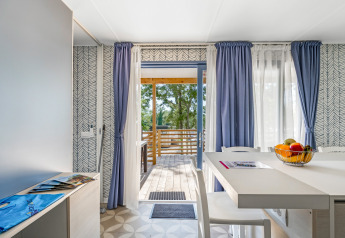 Interno della Mobile home Pula al Camping Bijela Uvala in Croazia, con vista su terrazza e alberi.