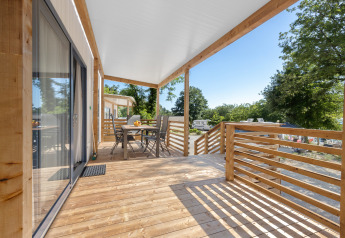 Veranda in legno della Mobile home Pula al Camping Bijela Uvala in Croazia, con tavolo e vista campeggio.