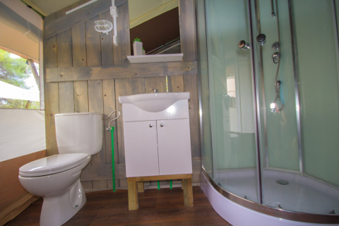 Salle de bain dans une tente safari avec toilettes, lavabo et douche au Camping Bijela Uvala en Croatie.