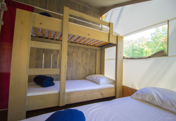 Vista interna di una tenda safari con letto a castello e letto singolo al Camping Bijela Uvala, Croazia.