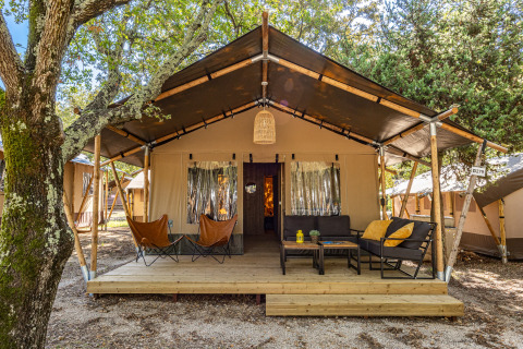 Safari tent Lodge with air conditioning at Camping Bijela Uvala in Croatia, featuring a cozy deck and seating.
