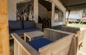 Siddeområde med træmøbler og blå puder i en safariteltsuite på Camping Bijela Uvala i Kroatien.