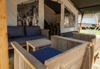 Zona de estar con muebles de madera y cojines azules en la Safari Tent Comfort en Camping Bijela Uvala, Croacia.