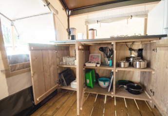 Åben køkkenskab i en safaritelt på Camping Bijela Uvala i Kroatien, med gryder, glas og køkkenudstyr.