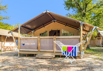 Vista exterior de una Safari Tent Lodge con tendedero y coloridas toallas frente a la entrada de la tienda.