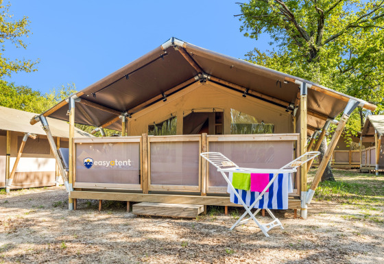 Vista esterna di una Safari Tent Lodge con stendibiancheria e asciugamani colorati davanti all’ingresso.