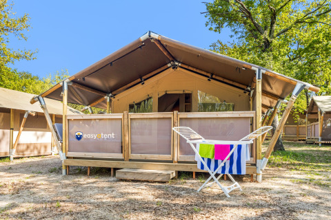 Vista esterna di una Safari Tent Lodge con stendibiancheria e asciugamani colorati davanti all’ingresso.