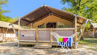 Buitenaanzicht van een Safari Tent Lodge met droogrek en kleurrijke handdoeken voor de tentingang.