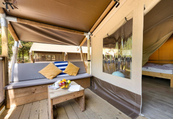 Entrée de la Safari Tent Lodge avec coin salon extérieur, coussins colorés et vue sur la chambre.