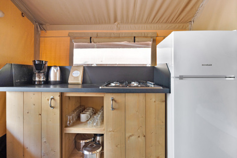 Petite cuisine au Safari Tent Lodge avec cafetière, bouilloire, plaques de cuisson, verres et frigo blanc.