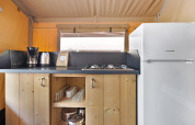Pequeña cocina en Safari Tent Lodge con cafetera, hervidor, estufa, vasos y un refrigerador blanco.
