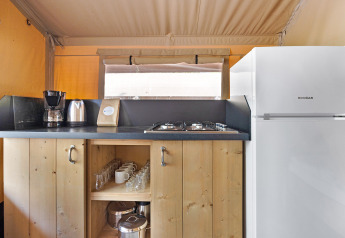 Angolo cottura nella Safari Tent Lodge con macchina del caffè, bollitore, fornelli e un frigorifero bianco.