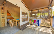 Safari Tent Lodge met houten meubels, stapelbedden, droogrek en uitzicht op het bos buiten.