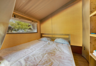 Interior de la Safari Tent Lodge en Camping Aminess Maravea, Croacia, con cama doble y ventana al exterior.