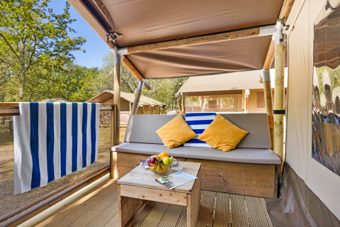 Gemütliche Veranda des Safari Tent Lodge auf Camping Aminess Maravea, Kroatien, mit Sitzbank, Tisch und Kissen.