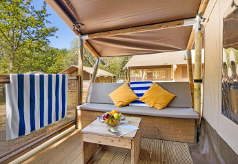 Zona de descanso exterior en Safari Tent Lodge, Camping Aminess Maravea, Croacia, con sofá, mesa y frutas.