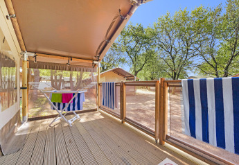 Holzveranda mit Wäscheständer und gestreiften Handtüchern an der Safari Tent Lodge unter blauem Himmel.