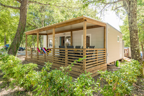 Mobil-home Fuskulin au Camping Bijela Uvala en Croatie, avec terrasse couverte, entouré d’arbres verdoyants.
