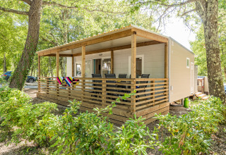 Mobilhjem Fuskulin ved Camping Bijela Uvala i Kroatien med en overdækket terrasse omgivet af grønne træer.