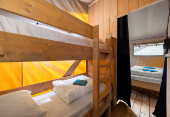 Vista interna di una tenda safari con letti a castello, letto matrimoniale, pareti in legno e aria condizionata in Croazia.