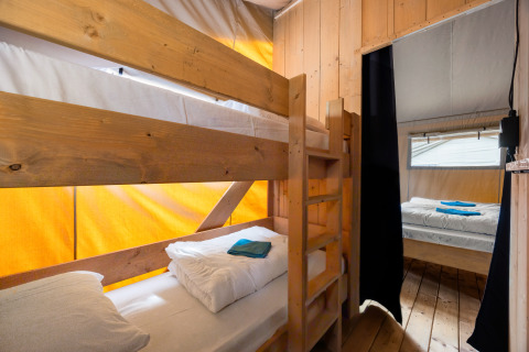 Interieur van een safaritent met stapelbedden, tweepersoonsbed, houten wanden en airconditioning in Kroatië.