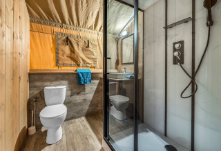 Baño dentro de una tienda safari con ducha, inodoro y lavabo en Camping Bijela Uvala, Croacia.