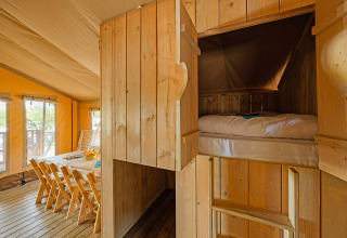 Interior de tienda safari en Camping Bijela Uvala, Croacia, con comedor y cama empotrada acogedora.