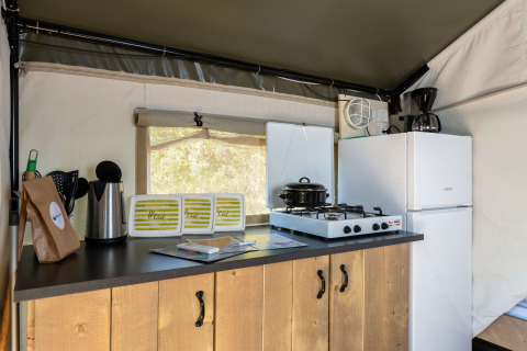 Área de cocina interior de la tienda Safari Tent Comfort en Camping Krk, Croacia, con estufa y nevera.