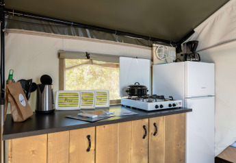 Área de cocina interior de la tienda Safari Tent Comfort en Camping Krk, Croacia, con estufa y nevera.