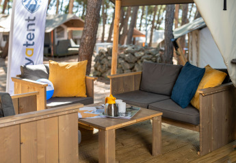Zona de estar exterior en la Safari Tent Comfort en Camping Krk, Croacia, con muebles de madera y cojines.