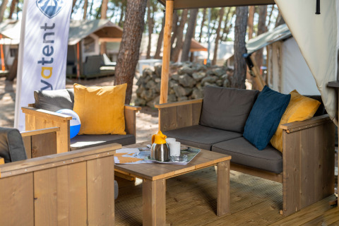 Area lounge esterna alla Safari Tent Comfort al Camping Krk in Croazia con arredi in legno e cuscini colorati.
