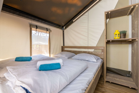 Innenansicht des Safarizelts Comfort auf Camping Krk in Kroatien mit Bett, Handtüchern und Regal.