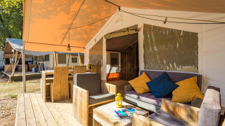 Safari Tent Luxury mit Holzterrasse, bequemen Sitzgelegenheiten sowie entspanntem Outdoor-Ambiente.