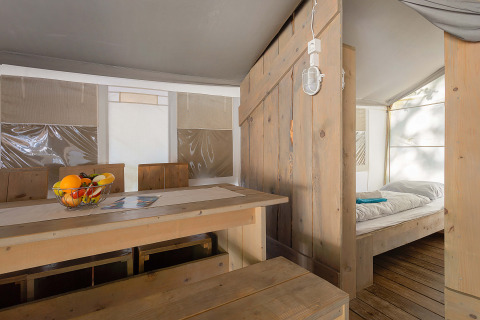 Interno della Safari Tent Luxury al Camping Bijela Uvala, Croazia, con zona pranzo e letto.