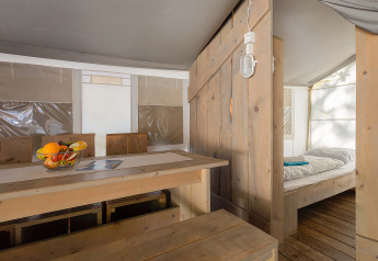 Interieur van de Safari Tent Luxury op Camping Bijela Uvala, Kroatië, met eethoek en bed.