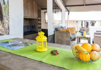 Interior de tienda safari con instalaciones sanitarias en Camping Aminess Maravea, Croacia, con frutero y farol.
