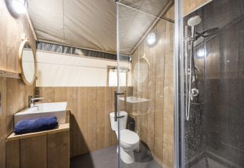 Bagno con pannelli in legno, doccia, WC e lavandino in una tenda safari al Camping Aminess Maravea, Croazia.