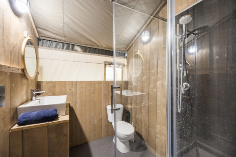 Badkamer met houten panelen, douche, toilet en wastafel in een safaritent op Camping Aminess Maravea, Kroatië.