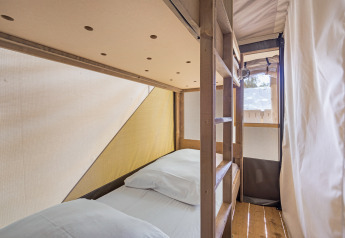 Binnenaanzicht van een safaritent met stapelbedden en houten vloer bij Camping Aminess Maravea in Kroatië.
