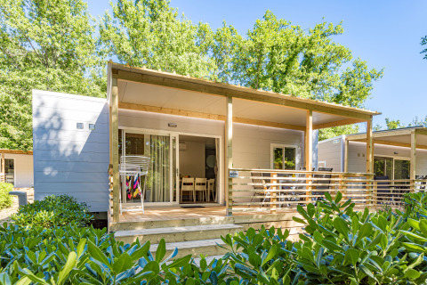 Mobile home Porec met overdekt terras, tuinmeubilair, droogrekje en veel groene beplanting rondom.