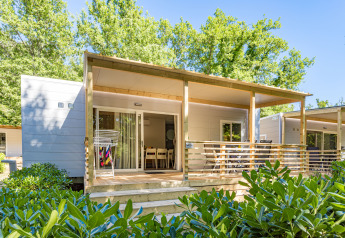 Mobile home Porec met overdekt terras, tuinmeubilair, droogrekje en veel groene beplanting rondom.