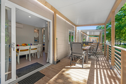 Veranda van Mobile home Porec met eettafel bij Camping Bijela Uvala Kroatië, omringd door bomen.