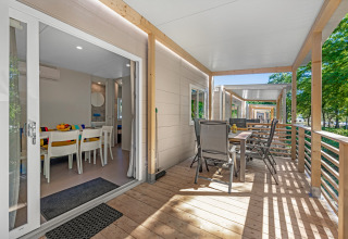 Veranda della Mobile home Porec con tavolo da pranzo al Camping Bijela Uvala in Croazia, vista alberi.